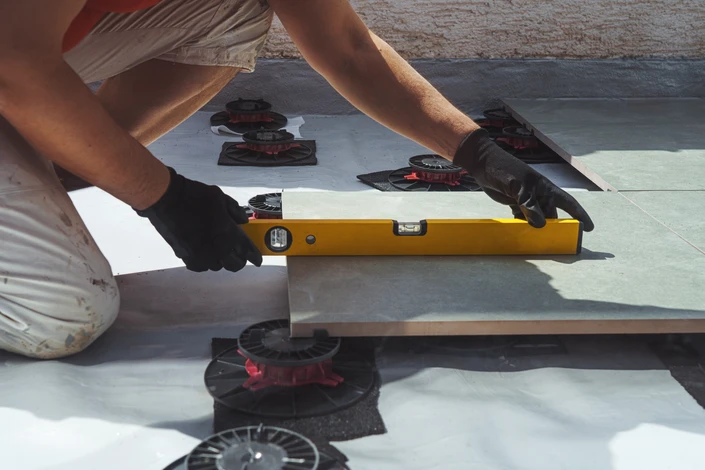 Vue en bas angle d'un travailleur avec des gants de protection marquant une place sur une planche en bois tout en la plaçant sur une fondation pour un patio extérieur